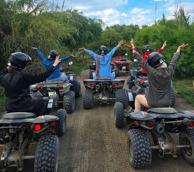 A group of people on ATVs on a dirt path surrounded by greenery. 4