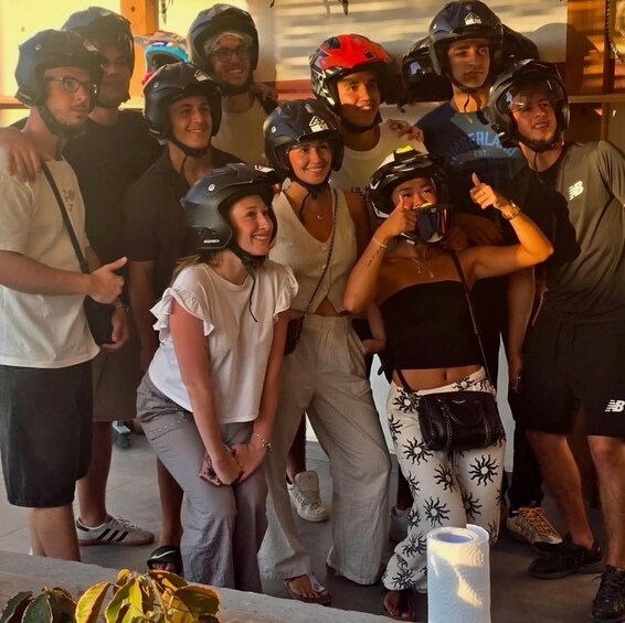 A group of people wearing helmets and casual clothing, standing indoors with a blurred background. 2