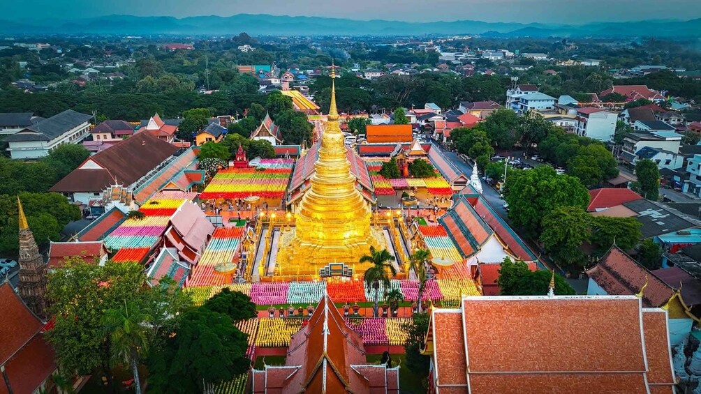 A golden stupa surrounded by colorful buildings and a mountainous landscape. 4