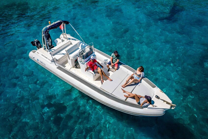 A small motorboat with four people on board, floating on clear blue water. 1