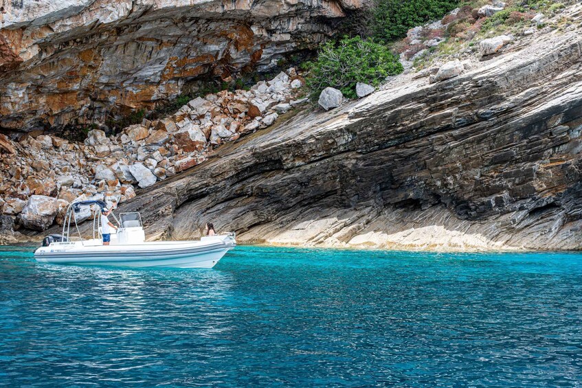 A boat on clear turquoise water near rocky cliffs. 3