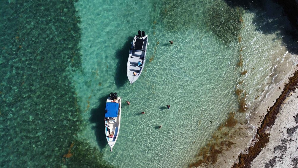 Two boats on clear turquoise water near a sandy beach. 5