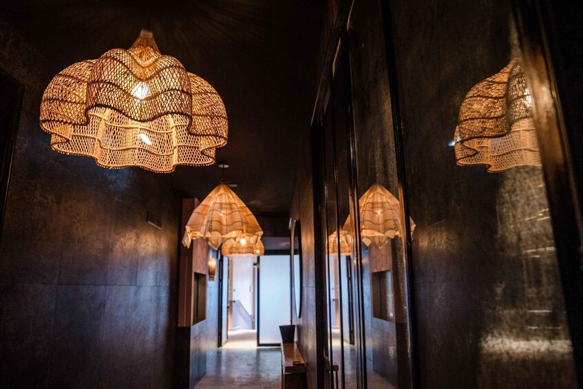 A corridor with hanging woven light fixtures and reflective surfaces. 3