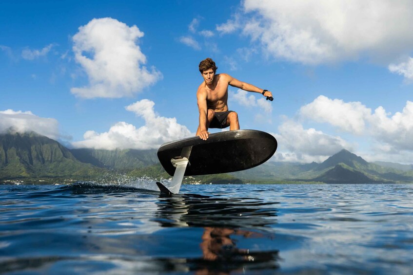 A person surfing on a wave with mountains in the background. 3