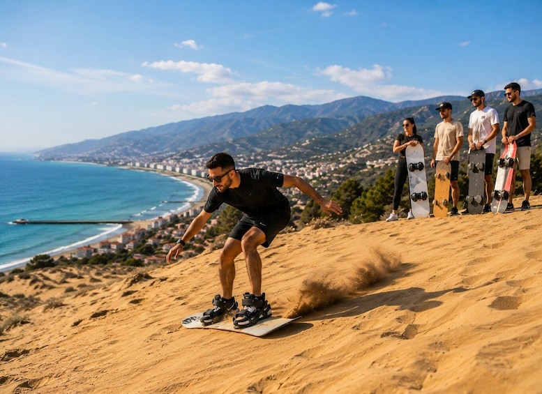 A person snowboarding down a sandy slope with a coastal town in the background. 2