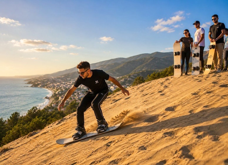 A person snowboarding down a sandy slope with a coastal town in the background. 1