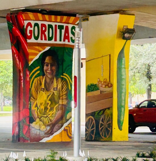 A mural with a woman cooking, labeled 'GORDITAS,' and a yellow wall with a vegetable cart. 2