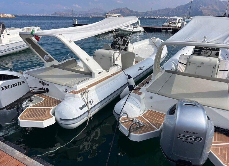 A white motorboat with a Honda outboard motor, docked at a marina with other boats. 1
