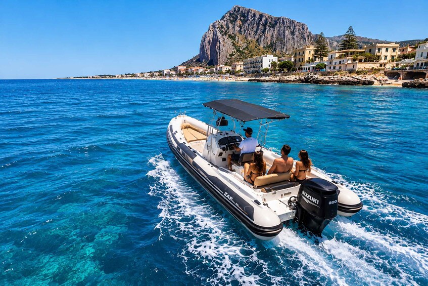 A motorboat with passengers on a clear blue sea, a rocky coastline, and buildings in the background. 3