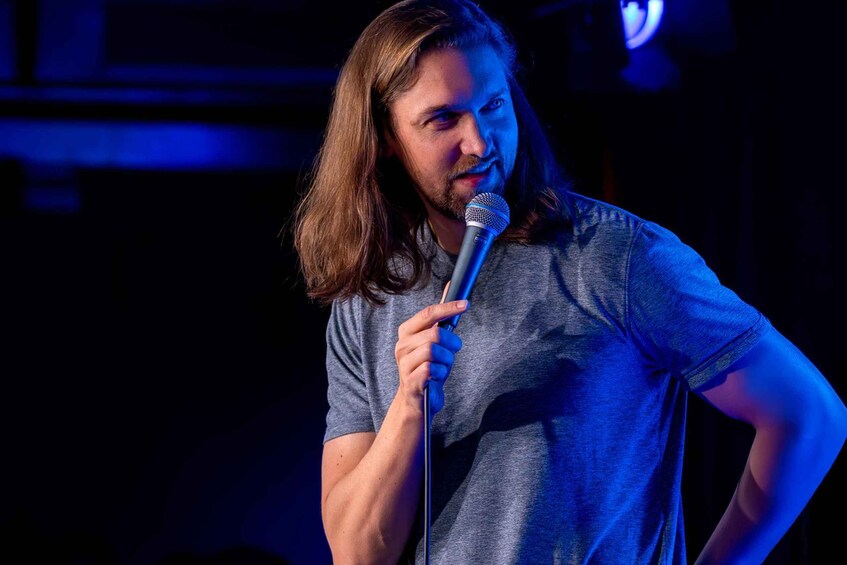 A person holding a microphone on a stage with blue lighting. 3