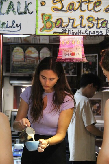 A person pouring a liquid into a cup at a cafe. 2