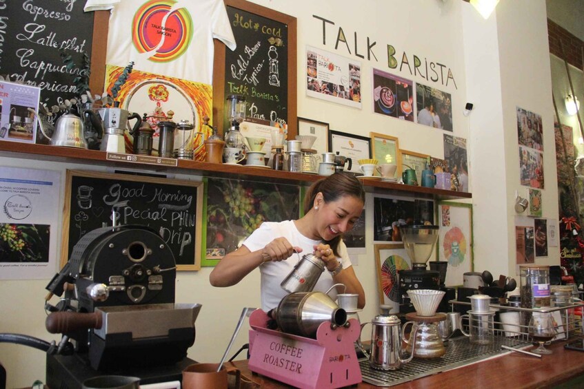 A barista preparing coffee at a coffee shop with various brewing equipment and a chalkboard menu. 1