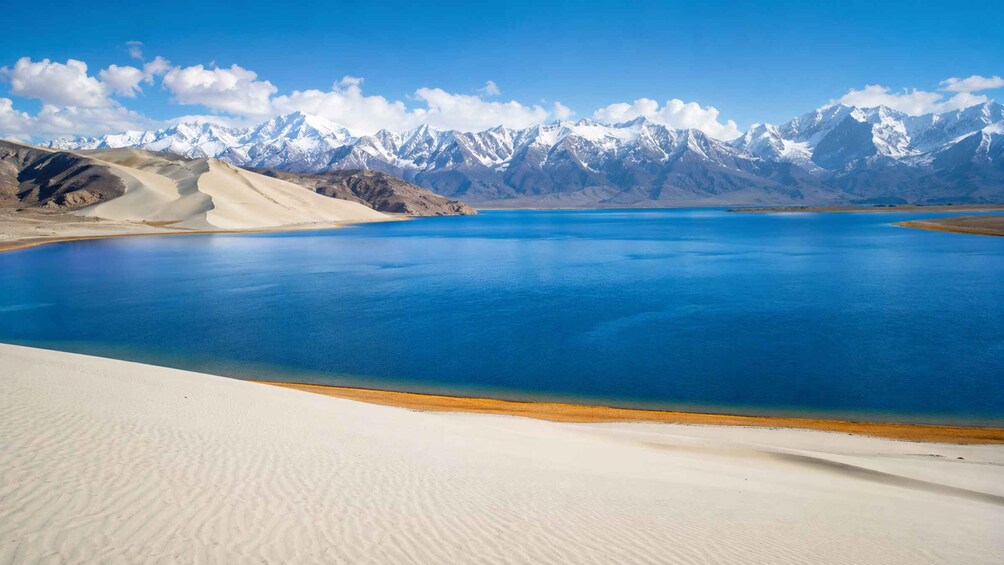 A desert landscape with a large body of water and snow-capped mountains in the background. 5