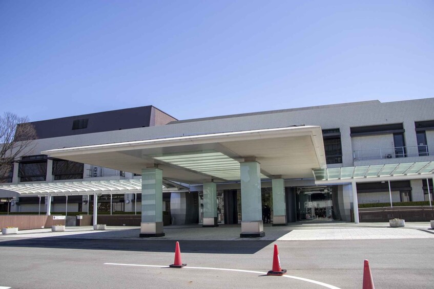 A modern building with a covered entrance, large columns, and a parking lot with cones. 4