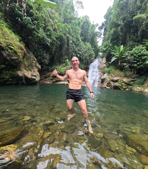 A person standing in clear water with a waterfall in the background. 2