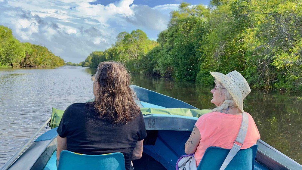 Two people on a boat, surrounded by a river and dense greenery. 1