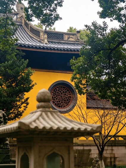 A traditional building with a yellow facade, a decorative window, and a stone pavilion in the foreground. 2