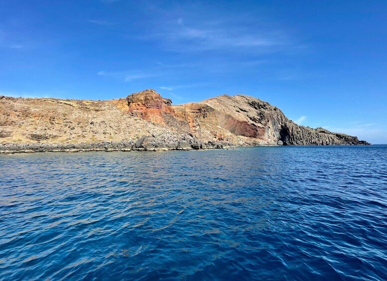 A coastal landscape with rocky cliffs and calm blue waters. 5