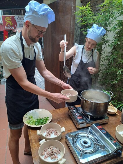 Two chefs preparing food outdoors with a stove and bowls of ingredients. 2