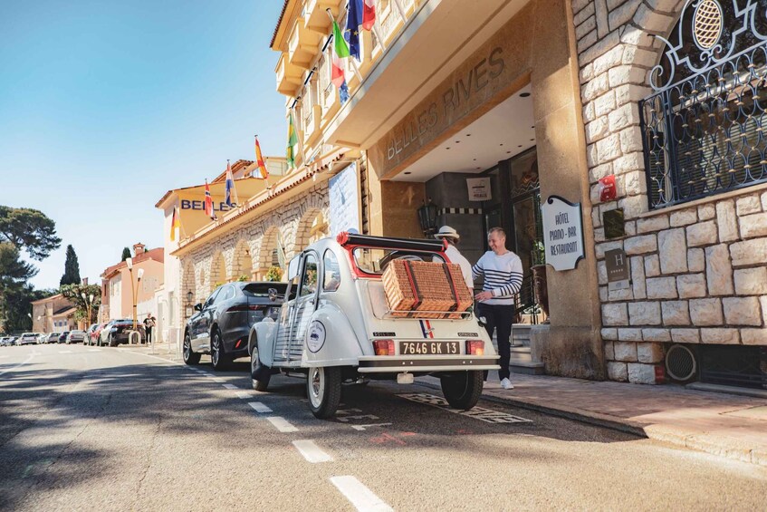 A vintage car parked in front of a building with a sign reading 'BELLES RIVES HOTEL PIANO BAR RESTAURANT.' 3