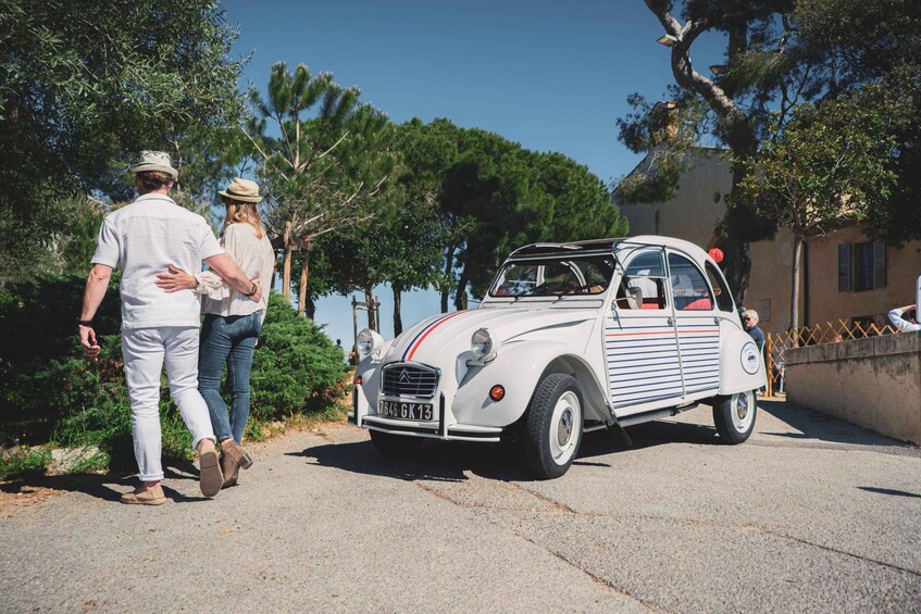 A vintage car parked on a street with people standing nearby. 5