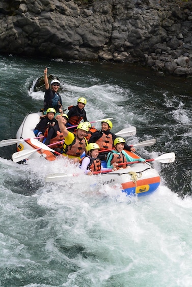 A group of people in a white and orange raft navigating a river with rapids. 3