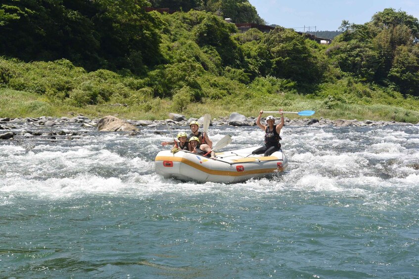 A group of people rafting on a river surrounded by greenery. 5