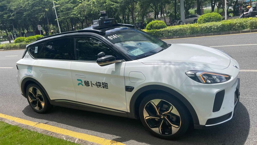 A white electric car with a roof box and a license plate number 0141 parked on the side of a road. 3