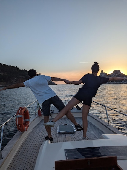 Two people on a boat, holding hands, with a sunset in the background. 4