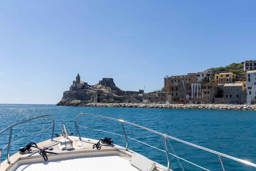 A boat on calm waters with a historic fort and coastal buildings in the background. 3