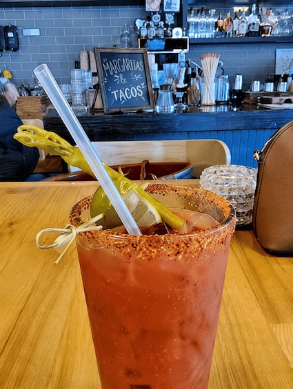 A margarita with a lime wedge and a straw on a wooden table. 3