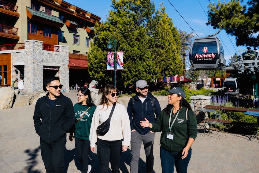 A group of people walking on a street with a ski lift in the background. 2