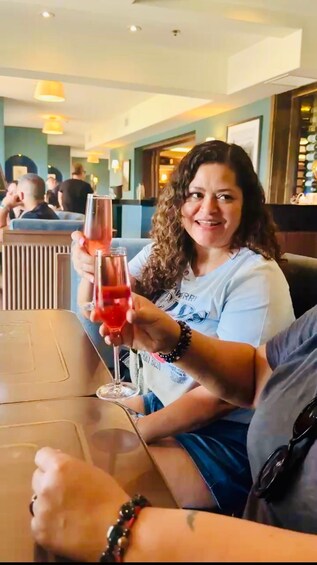 A person sitting at a table in a restaurant, holding a glass of red drink. 5
