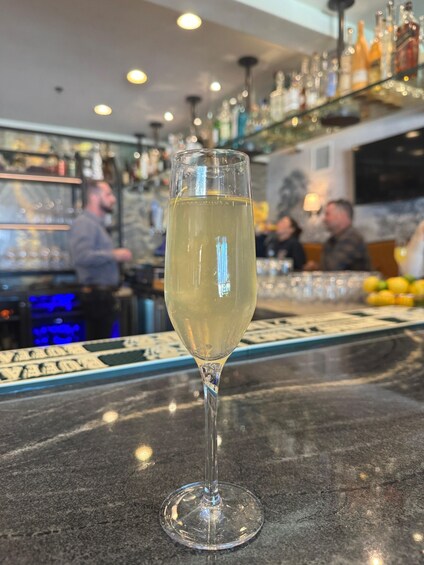A glass of white wine on a bar counter with bottles and glasses in the background. 5