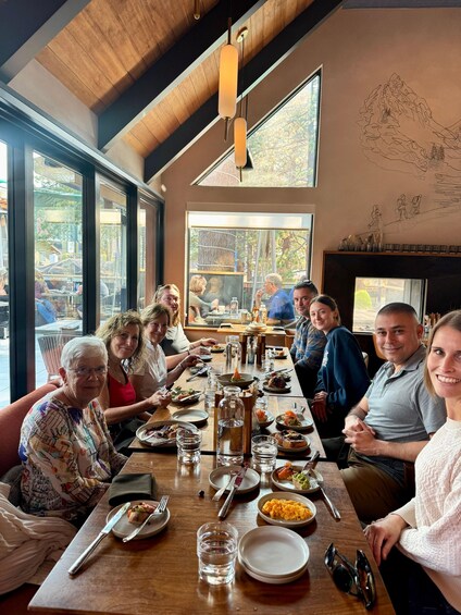 A group of people dining at a restaurant with wooden interiors and large windows. 2