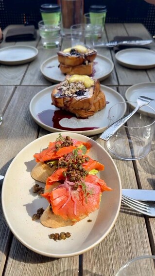 A wooden table with plates of food, including salmon and bread. 5
