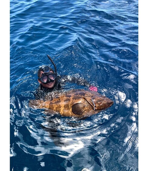 A person swimming with a large turtle in clear blue water. 4