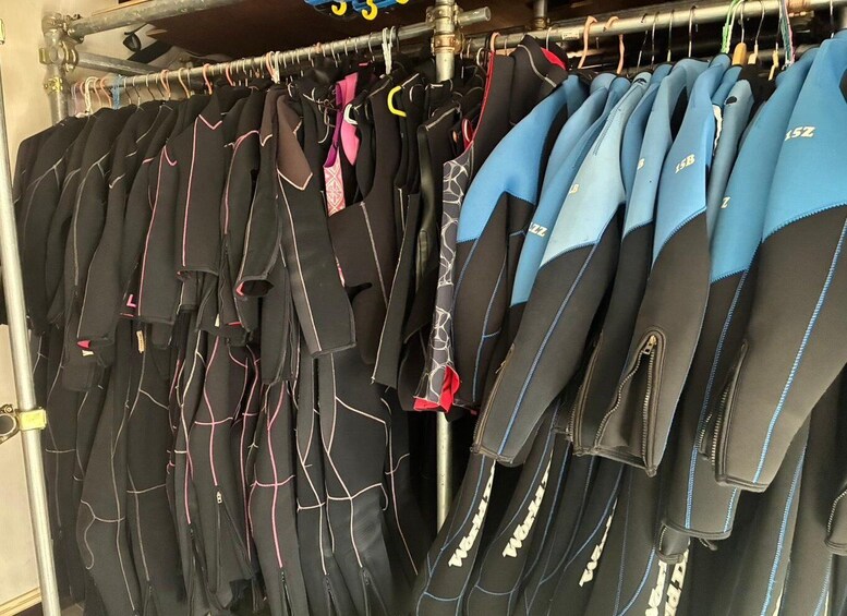 A rack of wetsuits with various designs and colors. 5