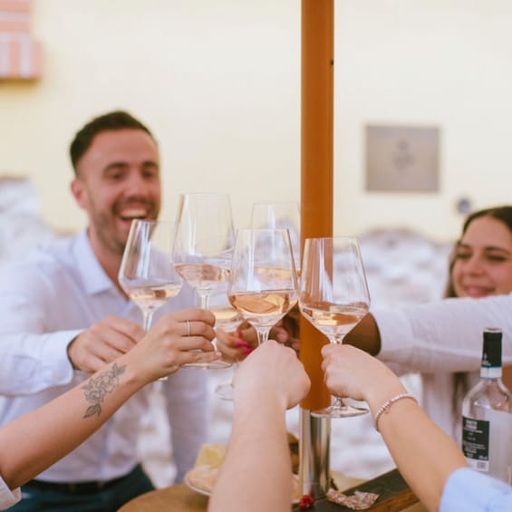 A group of people toasting with wine glasses around a table. 4