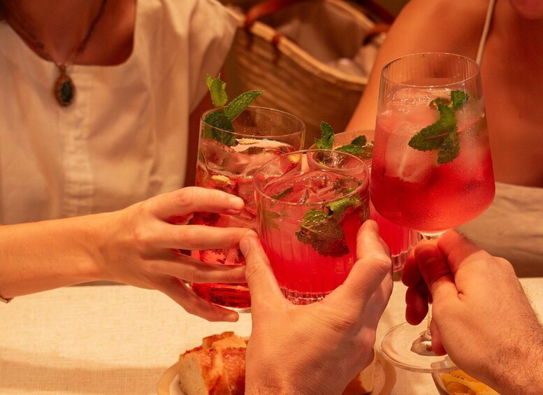 A group of people toasting with red drinks garnished with mint leaves. 1
