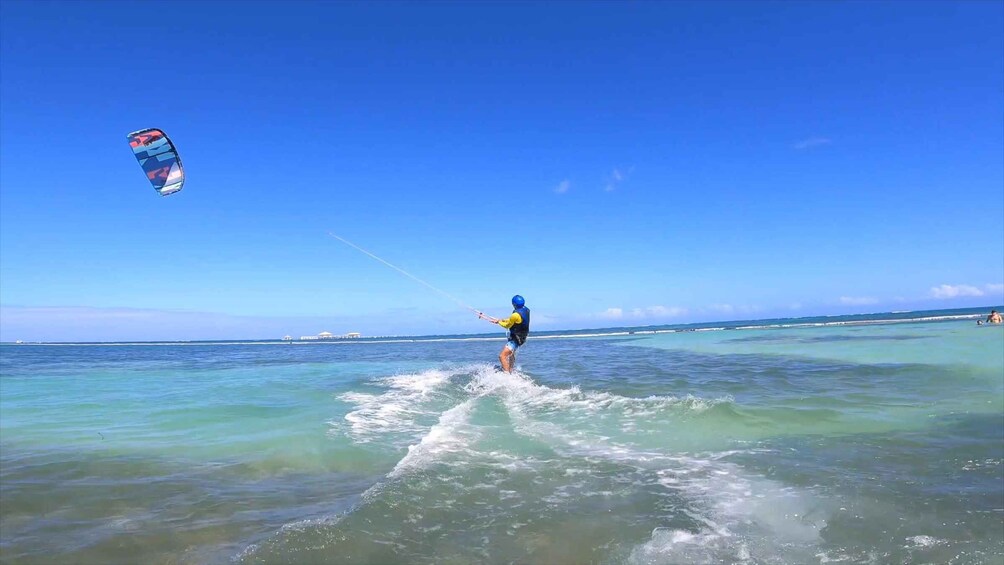 A person kiteboarding on a clear day over turquoise waters. 5