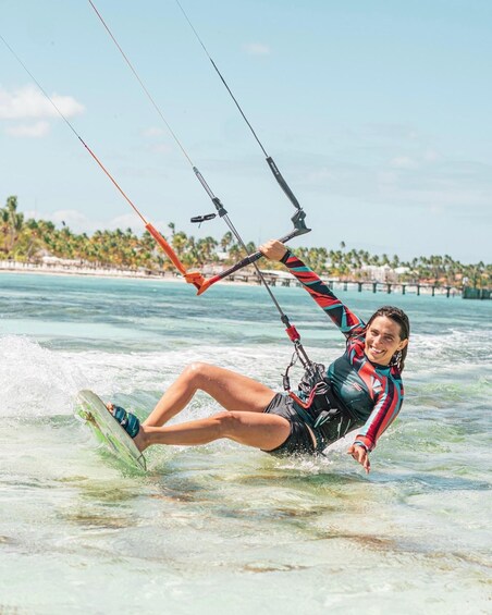 A person windsurfing on a clear day with a beach and palm trees in the background. 1
