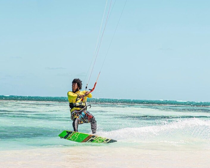 A person kiteboarding on a green board with a clear sky and calm sea. 2