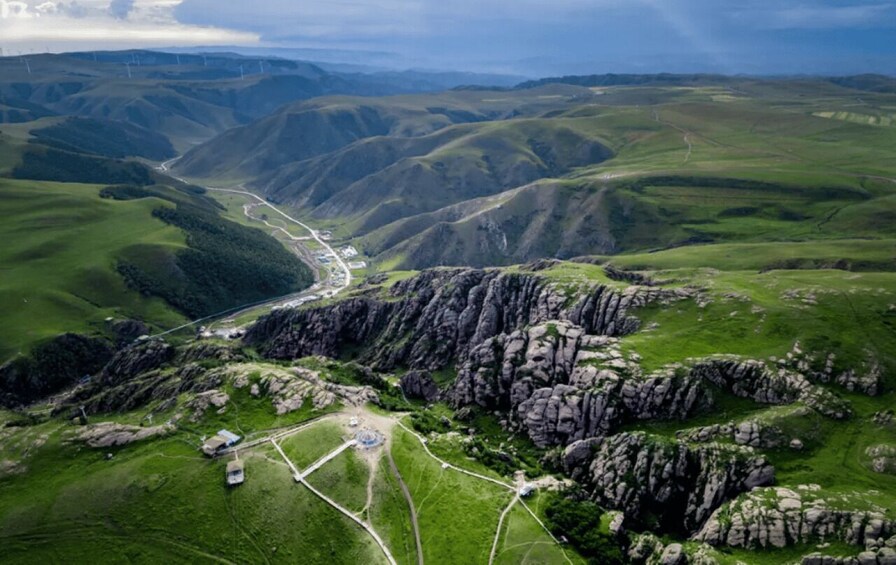 A mountainous landscape with winding roads, rocky outcrops, and green valleys. 2