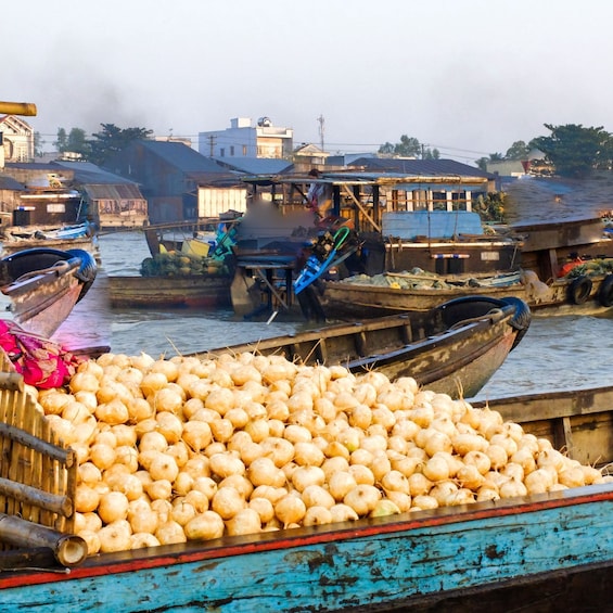A floating market with boats loaded with produce, including a large pile of ginger. 5