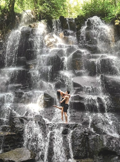 A waterfall with multiple tiers of cascading water surrounded by rocks and greenery. 5