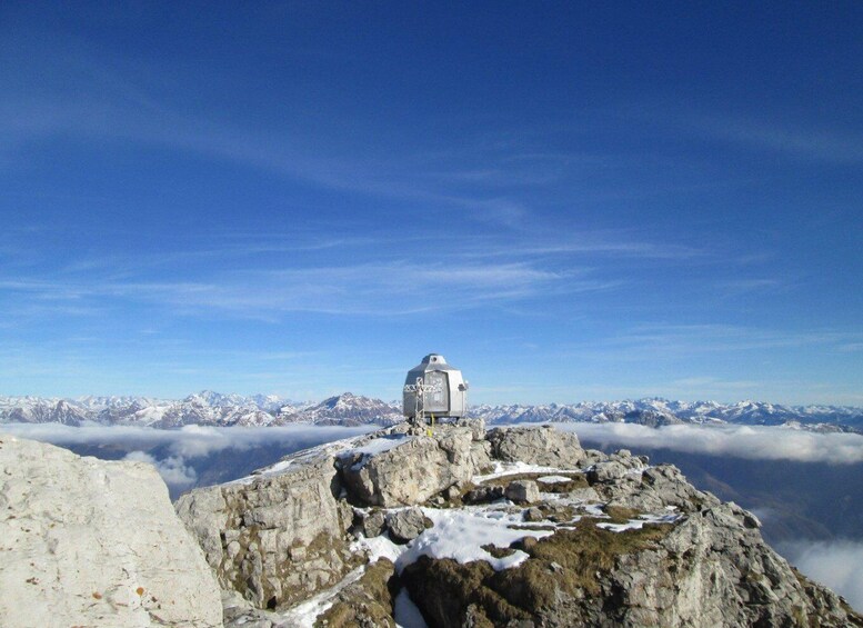 A mountain peak with a small observatory and snow patches. 1