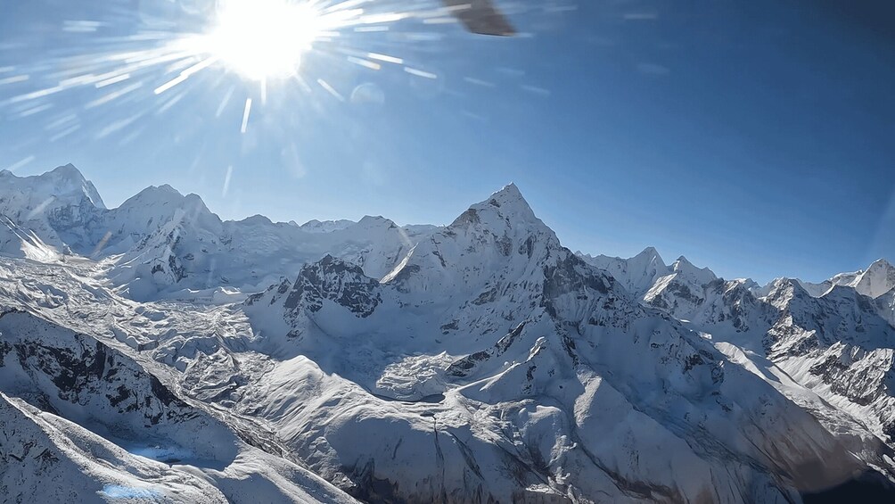 A snow-covered mountain range under a clear sky with the sun shining. 4