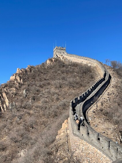 The Great Wall of China winding along a mountainous terrain under a clear blue sky. 1