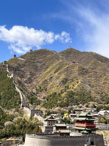 The Great Wall of China winding through a mountainous landscape with traditional Chinese architecture in the foreground. 5